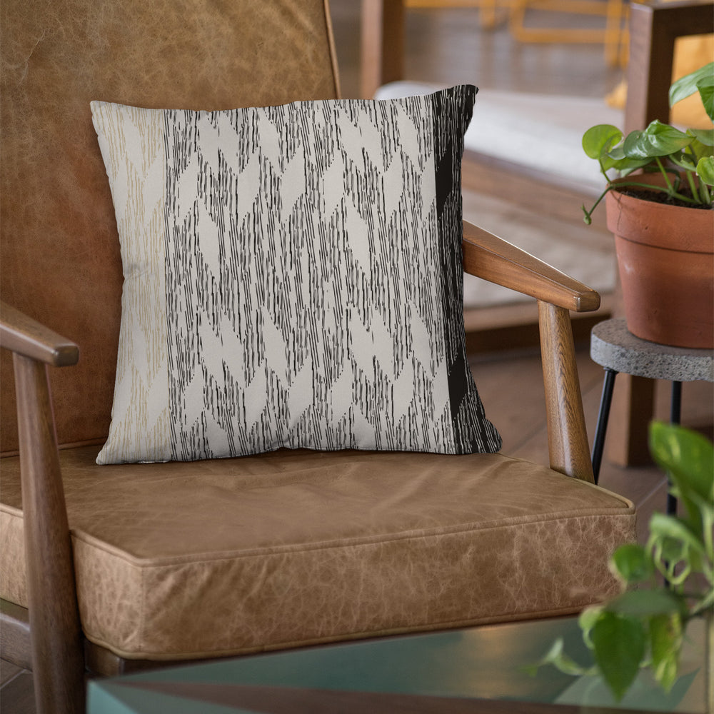 Black and Ivory Pili Square Pillowcase on a brown chair with plant and table accents on the side