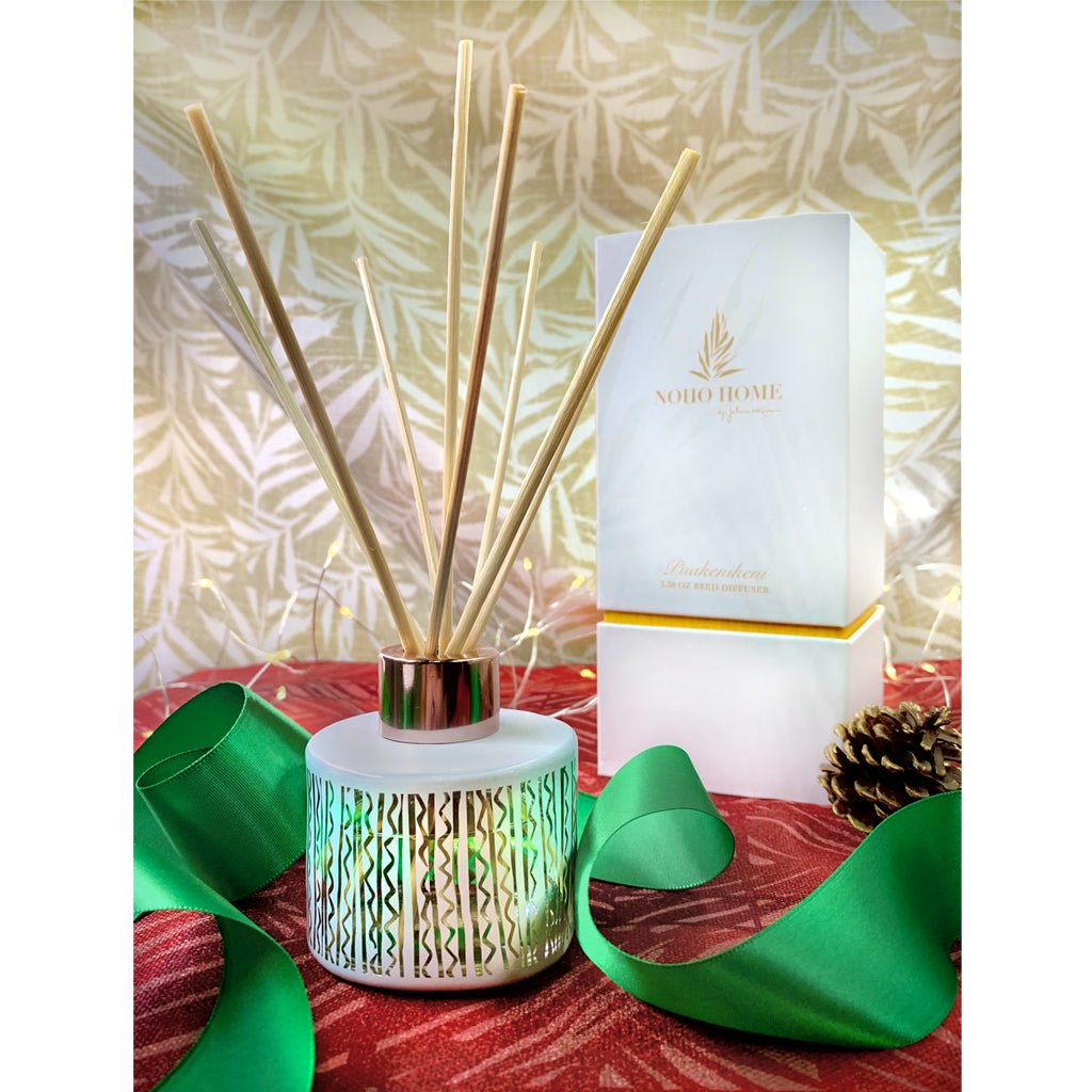 Puakenikeni Reed Diffuser and  its box with green ribbon and pine cone accent