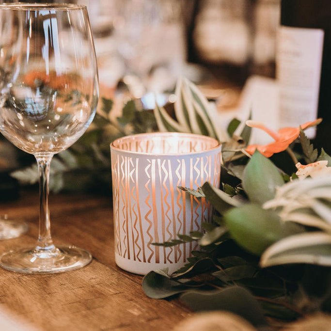 Puakenikeni Scent Soy Candle and wine glass placed on a table, creating a cozy and intimate atmosphere.