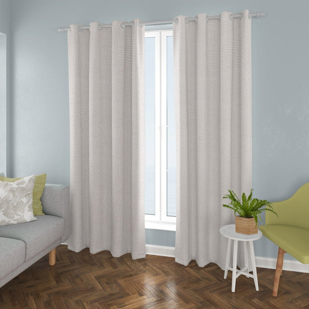 'Upena Drapery against a pale blue wall, with grey sofa and accent pillows as well as a little table and accent chair.